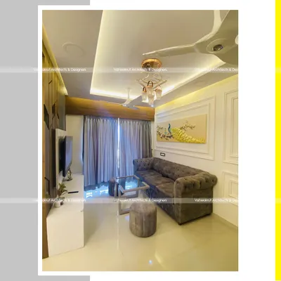 A view of a completed living room in Dronagiri, Uran. The design features a comfortable tufted sofa, elegant wall molding, and a striking 3D peacock wall art piece that serves as a focal point.
