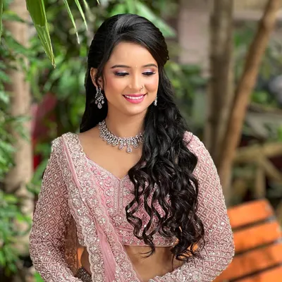 A beautiful engagement bride in a baby pink lehenga. She is wearing a delicate, single-line diamond necklace with matching earrings, perfect for a subtle yet elegant look.