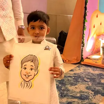 A young boy in a kurta holds his caricature at a family function. My drawings are always a huge hit with the kids.