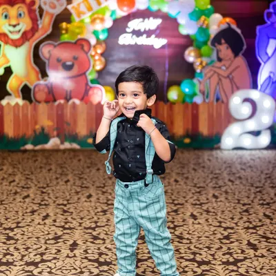 The birthday boy, turning two, strikes a cool pose in front of his jungle-themed party decorations.