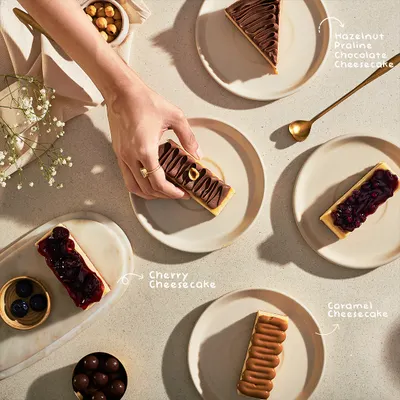 Decisions, decisions. An overhead shot of my cheesecake selection, including Hazelnut Praline, Cherry, and Caramel cheesecakes, inviting you to pick your favorite.