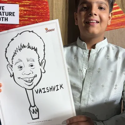 A young boy in traditional wear proudly holds up his black and white ink caricature. The simple, bold lines really capture his cheerful expression.