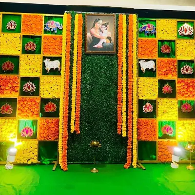 A vibrant and creative backdrop for a Sreemantham. This wall is made of fresh marigolds in a checkerboard pattern, with traditional motifs and a portrait at the center.