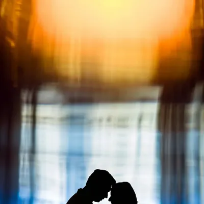 An abstract and artistic silhouette of a couple. The vibrant, warm colors in the background create a painterly effect, focusing on the intimate connection in their outline.