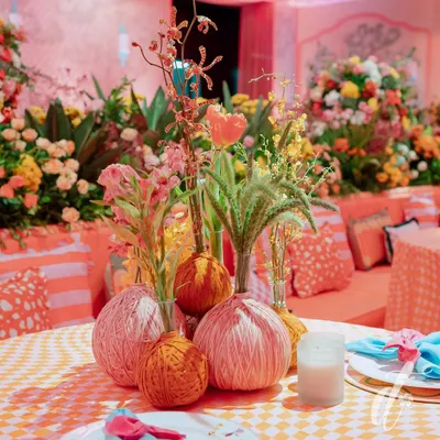 For our 'La Dolce Vita' theme, we created these unique centerpieces by mixing fresh flowers with textured yarn-wrapped spheres, adding a playful and crafty element to the tablescape.