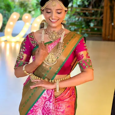 A beautiful muhurtham look featuring a traditional temple jewellery set on a pink and green patola saree. The matha patti and layered necklaces create a classic South Indian bridal look.