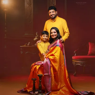 A stunning family portrait from a traditional maternity photoshoot. The rich colors of the saree and the classic studio backdrop create a regal and timeless image.