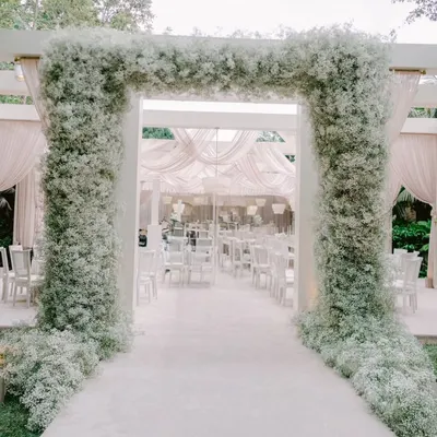 A breathtaking entrance for an all-white themed event. The grand archway is completely covered in clouds of baby's breath, creating a magical and ethereal passageway for guests.