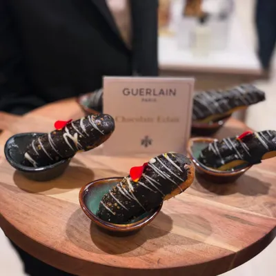Decadent Chocolate Éclairs created for a luxury event. Each choux pastry is filled with cream and topped with a glossy chocolate glaze and a delicate edible flower.