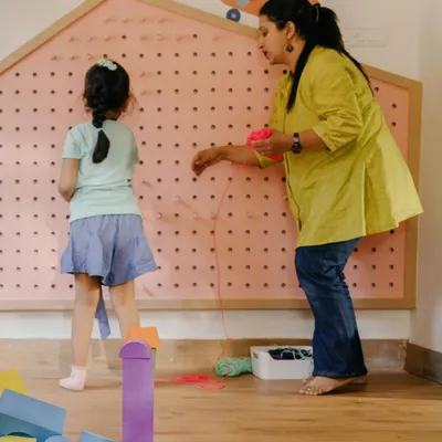 This is our Makerspace, a hub where children can invent, tinker, and design. A child and teacher work together on a large weaving board, developing fine motor skills and collaborative problem-solving.