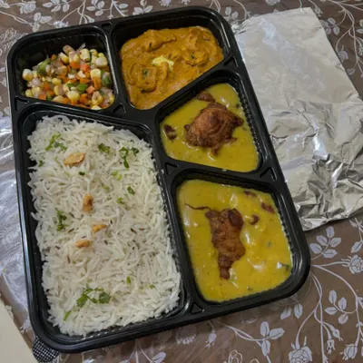 A classic North Indian meal box featuring Jeera Rice, creamy Paneer Butter Masala, Kadhi Pakoda, a fresh corn salad, and soft rotis packed separately to stay fresh.