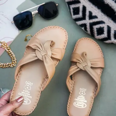 A lifestyle shot of a hand holding a pair of beige sandals, with sunglasses and a bag as props. This creates a 'get ready with me' vibe that is very popular on social media.