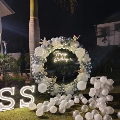 The combination of a 'Happy Birthday' neon sign and large, illuminated 'SS' initials makes this outdoor setup feel personal and look professional. These lighting elements are central to the design.