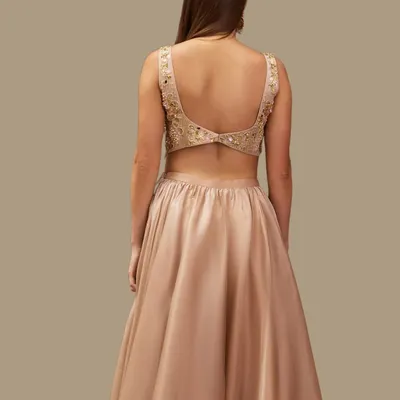 The back of this champagne gold lehenga shows off a beautifully detailed, hand-embroidered blouse. It's a timeless design that celebrates grace and elegance.