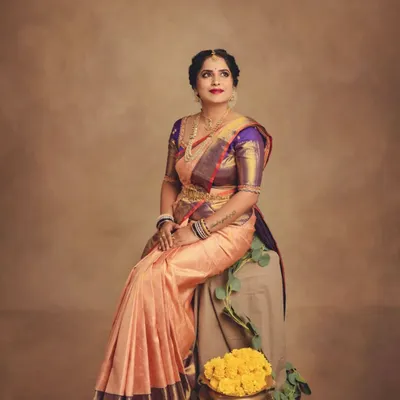 A beautiful seated pose that captures the regal feel of a traditional saree look. The composition is balanced with marigolds and greenery, adding a festive touch to this classic portrait.