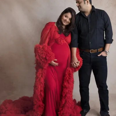 A classic couple's pose. Dressed in a stunning red gown, she holds hands with her partner, capturing the simple, powerful connection between them.