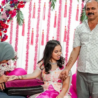 A touching moment between a father and daughter during her Mehendi ceremony. He proudly shows off a temporary tattoo of her wedding date on his arm.