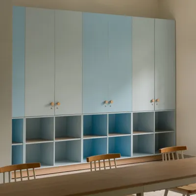 Custom storage solutions in one of the activity rooms. The combination of closed cabinets and open cubbies, finished in a calming two-tone blue, provides ample, organized space for materials.