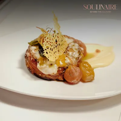 An exquisite example of modern plating, where a delicate parmesan crisp adorns a savory creation. This dish embodies our philosophy of turning food into art.
