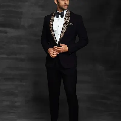 This black tuxedo features a unique embroidered shawl lapel, giving a modern twist to a classic style. It's the perfect outfit for a groom who wants to look sharp and sophisticated at his reception.