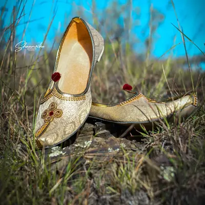 The groom's traditional shoes (jutti), placed in a natural, grassy setting. I believe in capturing every detail that completes the wedding look.