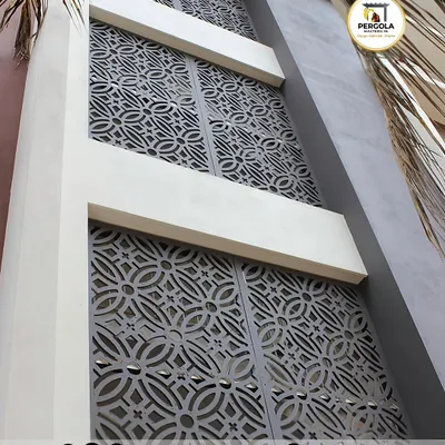 These large, laser-cut metal screens feature a traditional geometric pattern, serving as a decorative facade for a modern building. The panels add a layer of privacy and architectural interest while allowing light to filter through.