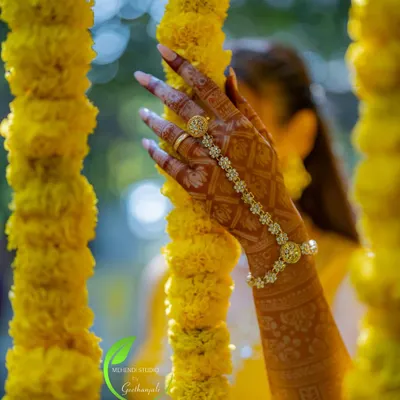 A beautiful, artistic shot of the bride's mehendi, with her hand elegantly placed among marigold flower strings.