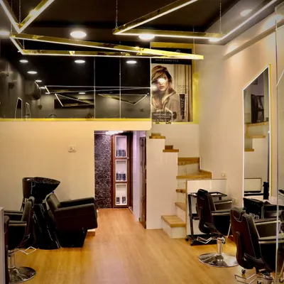 This is a wide view of my salon, showcasing the modern aesthetic with gold accents and a mezzanine level. I ensure the entire space is spotless and inviting for every client.