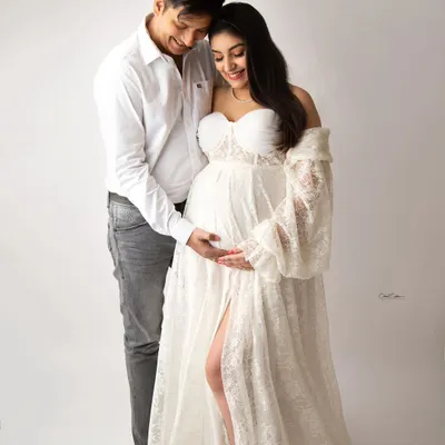 A beautiful, tender moment between parents-to-be. They are both dressed in white, creating a light and airy feel for this classic couple's maternity portrait.