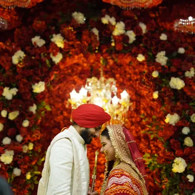 An intimate moment between the Sikh bride and groom against a wall of red flowers. This is the kind of quiet, romantic shot that tells a powerful story.
