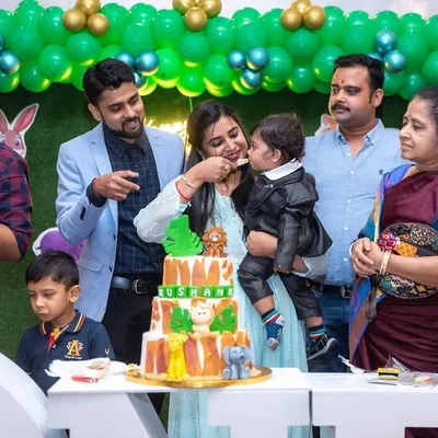 A heartwarming candid shot of a mother feeding her son his first taste of birthday cake, surrounded by smiling family members. These are the authentic, story-telling images we love to capture.
