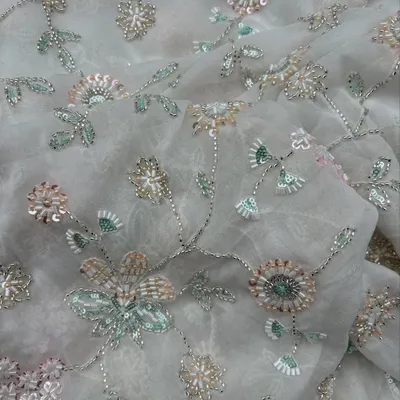 This embroidered georgette features delicate floral vines with sequin and bead work, adding a touch of sparkle to its breezy texture. Perfect for gowns and lehengas.