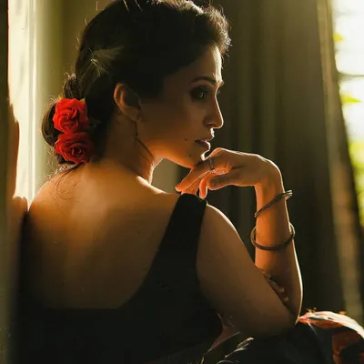 This portrait uses natural light and shadow to create a soft, romantic mood. The pose, looking back over the shoulder with flowers in her hair, has a classic elegance, while the lighting gives it a modern, cinematic feel.