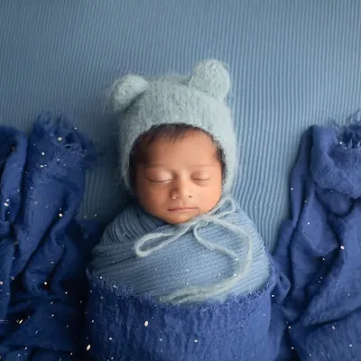 This little one is so cozy in shades of blue. A simple swaddle and a matching bear bonnet are all that's needed to create a timeless and adorable portrait.
