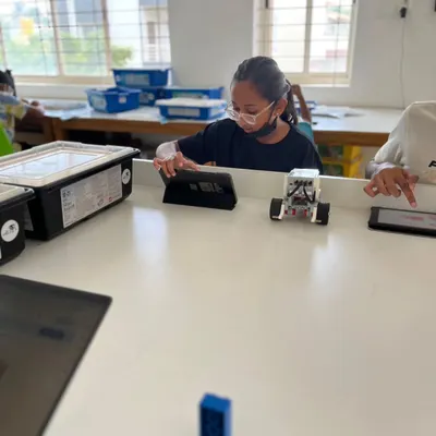 A student uses a tablet to program her robot in our well-equipped classroom. We provide the latest tools, including LEGO Education and Arduino kits, to facilitate a modern STEM learning experience.