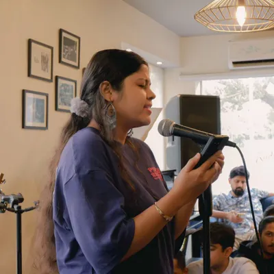 A student sharing her poetry and music at a recital. These intimate sessions are a space for all forms of artistic expression.
