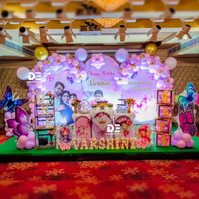 A spectacular butterfly-themed first birthday stage for Varshini. I used a personalized photo backdrop, a lavender balloon arch, and large, shimmering butterfly cutouts to create this enchanting scene.