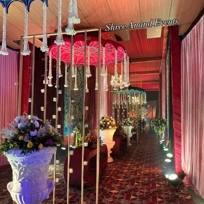 A welcoming pathway for guests, lined with traditional Rajasthani umbrellas, candle-lit partitions, and large floral urns, creating a warm and inviting atmosphere.