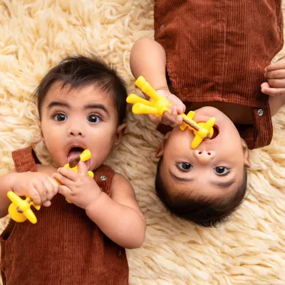 Teething time for two! This adorable shot captures twin brothers at their 6-month sitter session, each with their own teether. It's a fun way to document this milestone.