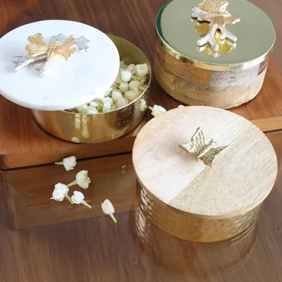 A stunning trio of our decorative keepsake boxes. This image showcases the different materials and designs we offer, from a hammered gold box with a wooden lid to a marble-lidded box with mixed-metal accents.