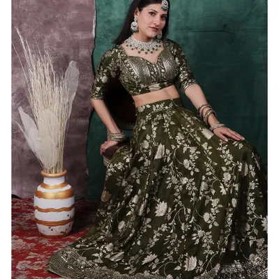 A full portrait showcasing a stunning olive green lehenga. The studio lighting is set to bring out the silver floral embroidery and the sparkle of the diamond jewellery, creating a look of pure royalty inspired by classic period dramas.