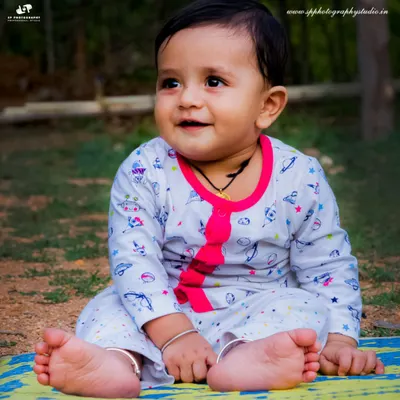 An outdoor baby photoshoot allows us to capture your little one exploring the world. This portrait of a baby sitting happily on a mat shows the simple, beautiful results of a natural light session.
