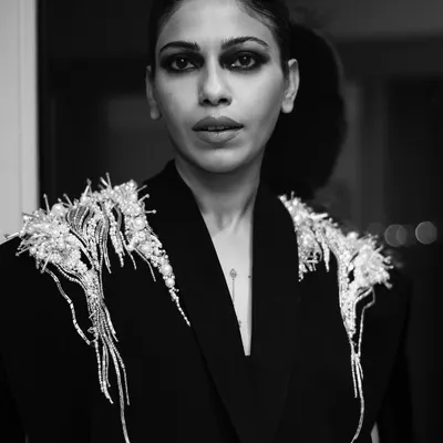 A close-up black and white portrait of Anasuya Sengupta. The focus here is on her expressive eyes and the intricate details of the Gaurav Gupta design, capturing a moment of quiet intensity.