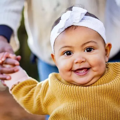 That big, gummy smile is just the best. This close-up captures the pure happiness of a baby who is learning to stand with a little help.