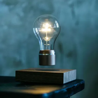 The FLYTE light bulb creates a warm, ambient glow perfect for setting a relaxing mood. This atmospheric shot captures the bulb floating in a dimly lit space, highlighting its function as both a light source and a piece of art.