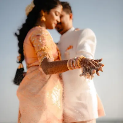 A close-up of the couple's hands, covered in sand, during their beach pre-wedding shoot. This shot focuses on the tactile details and the intimacy of their embrace by the sea.