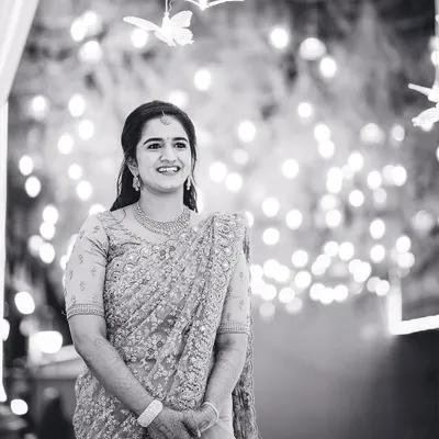 A beautiful candid portrait of the bride, her smile illuminated by the soft glow of background lights. Black and white enhances the emotion and timelessness of the moment.