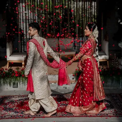 A magical moment with the couple walking hand-in-hand amidst a shower of red petals. This shot, taken at the dreamy Amitarasa venue, showcases our cinematic style in creating fairy-tale portraits.