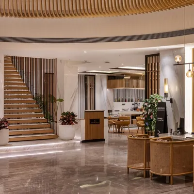 The main lobby and reception area of Radisson Resort, Khopoli, showcasing a cohesive design language. Polished marble floors, wood-slatted ceilings, and thoughtfully placed furniture create a warm and welcoming atmosphere for arriving guests.