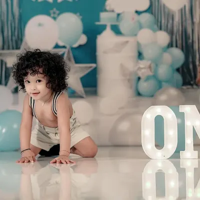Celebrating the big ONE! This little boy is crawling towards the light-up 'ONE' sign in our beautifully decorated blue and white birthday setup.